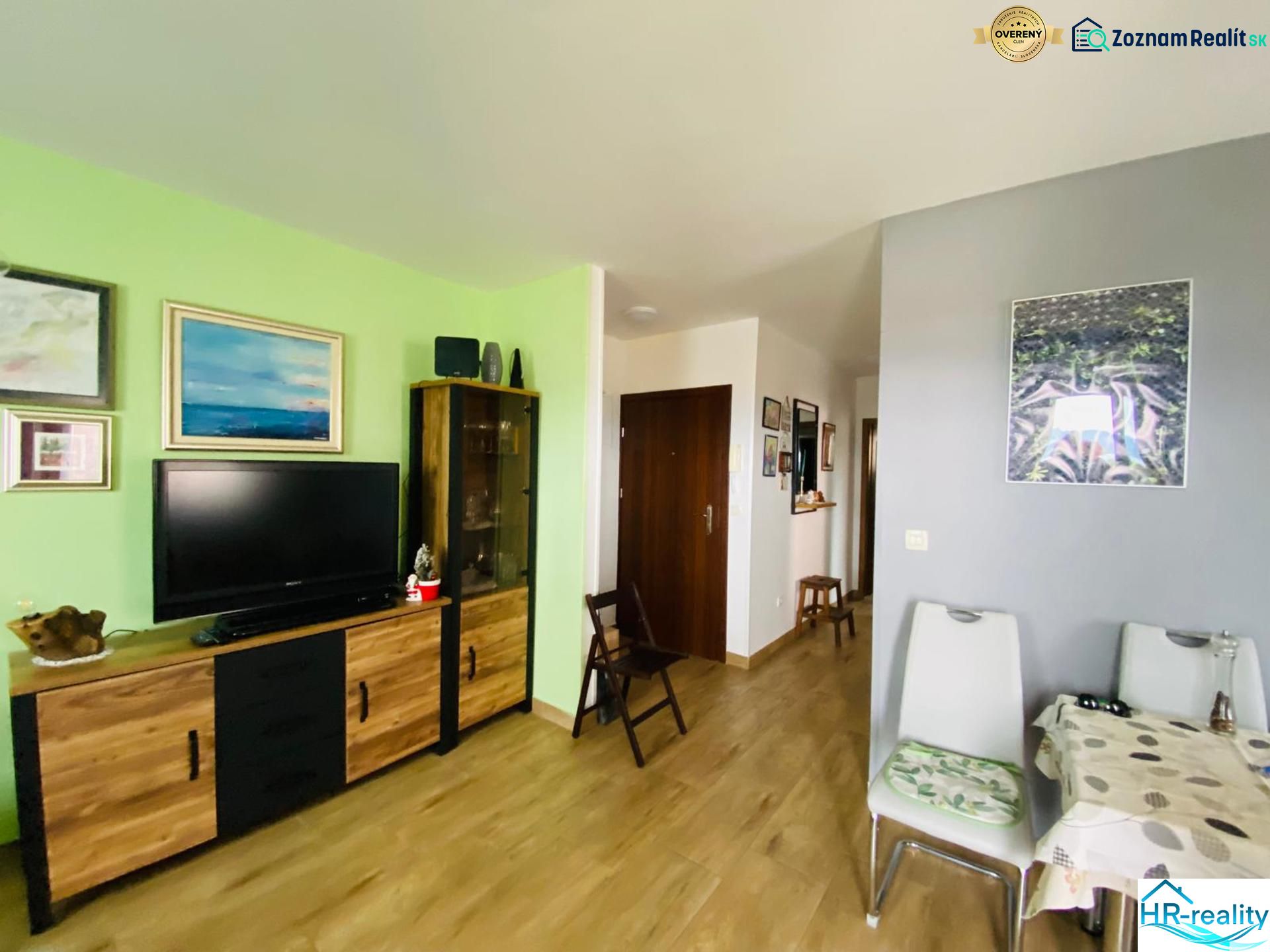 Obývací pokoj v rekreačním apartmánu s televizí a dekoracemi, podlaha s dřevěným dekorem.
