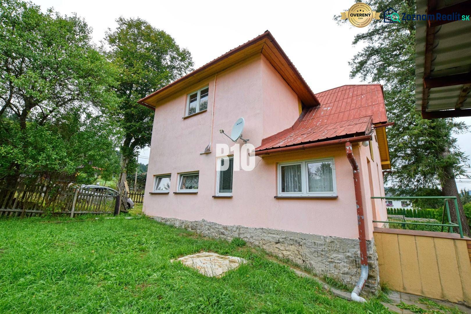 Rodinný dům v Makově s růžovou fasádou, zahrada a satelitní anténa na stěně.
