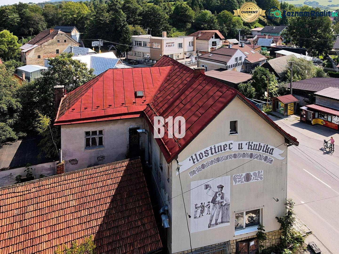 Hostinec v Bílé s červenou střechou a nástěnnou malbou muže s pivem.
