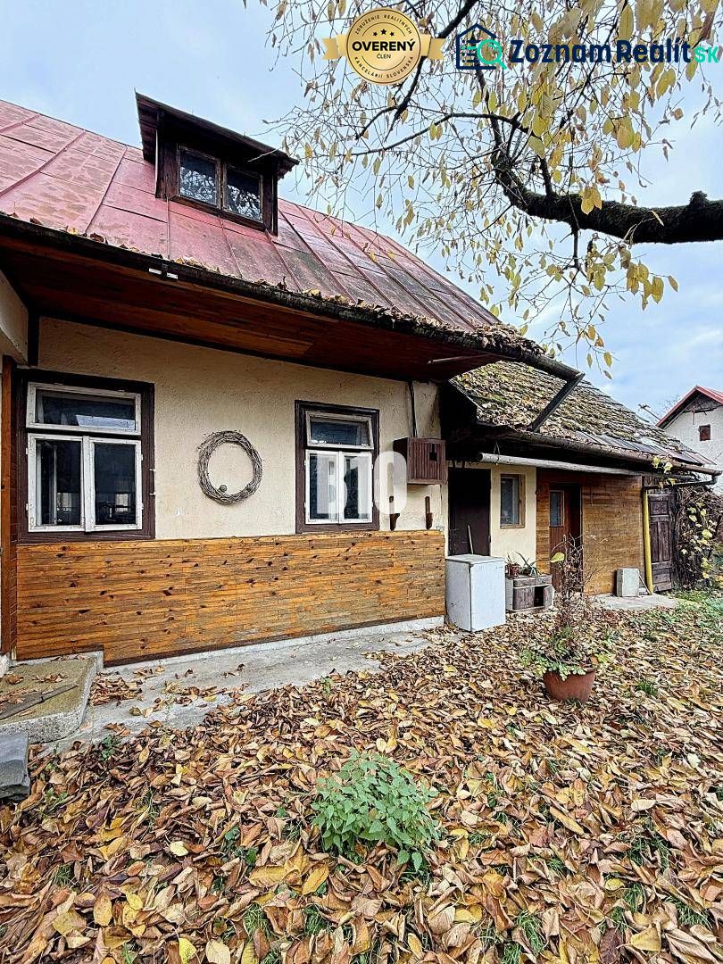 Rodinný dům v Kotešové se starým dřevěným opláštěním a padajícím listím na zahradě.