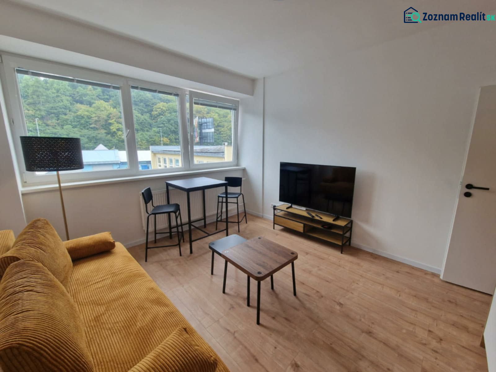 Obývací pokoj s pohovkou, televizorem a podlahou s dřevěným dekorem v 2pokojovém bytě.