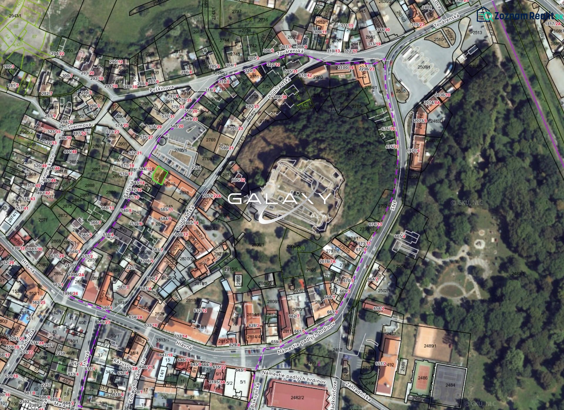 Letecký pohled na pozemky v historickém centru Fiľakova, obklopené budovami a zelení.