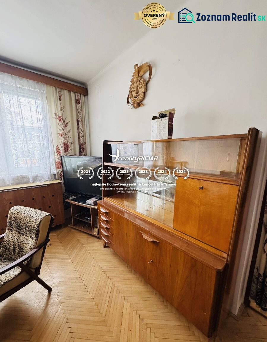 Pohled do obývacího pokoje s retro nábytkem a podlahou s dřevěným dekorem ve 3-pokojovém bytě.