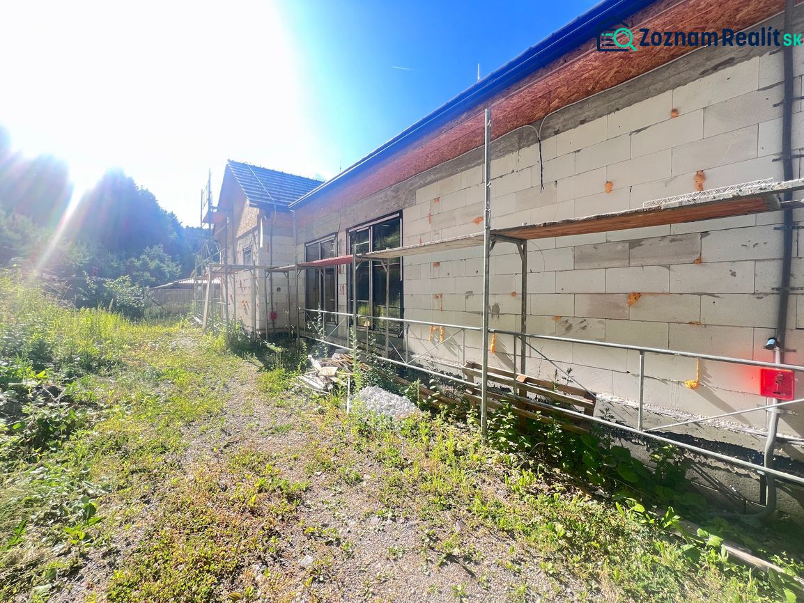 Výstavba rodinného domu v Badíně, okres Banská Bystrica, se zeleným okolím a lešením.