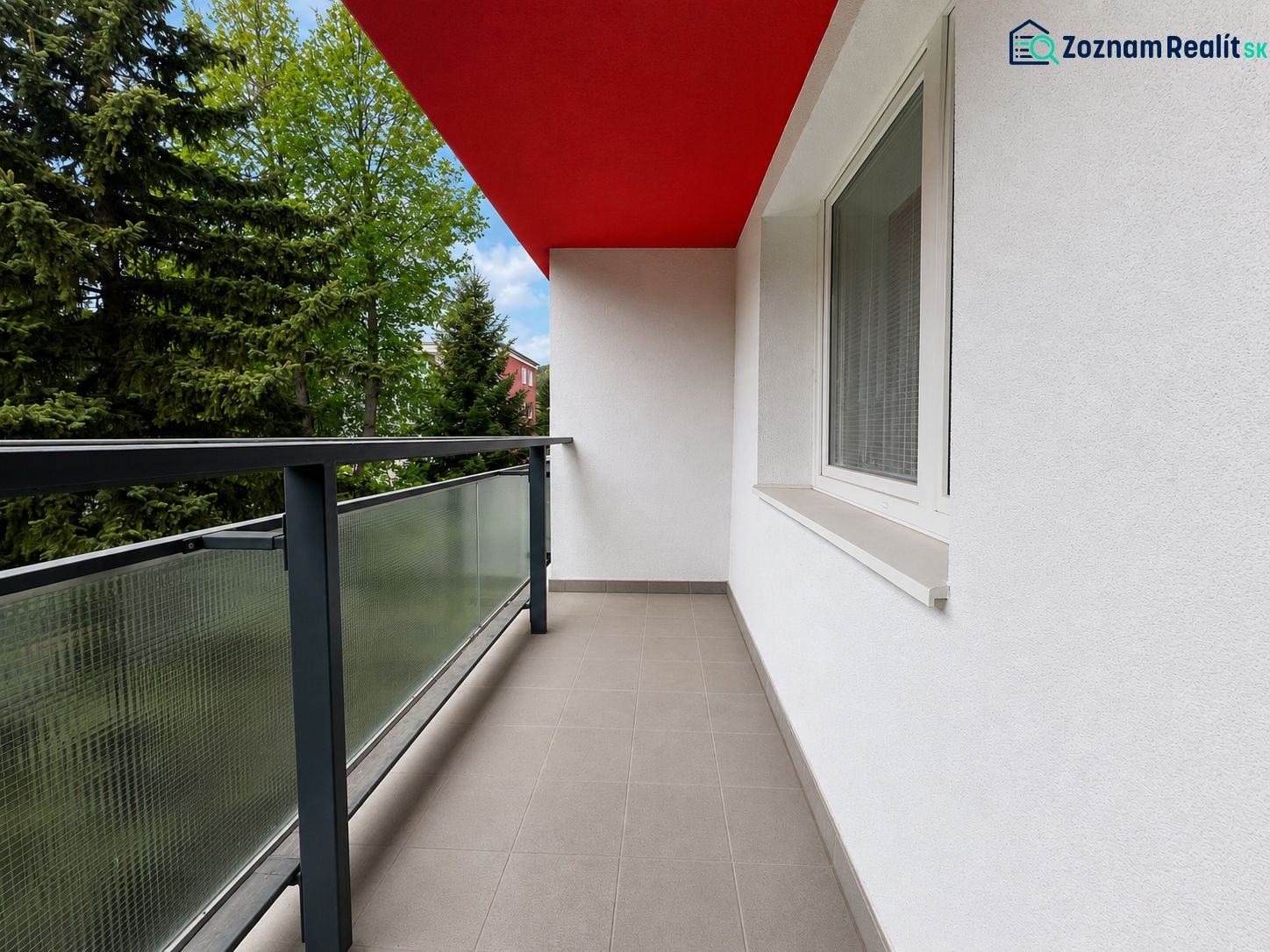Balkon z 2pokojového bytu s červeným stropem a zábradlím se sklem.