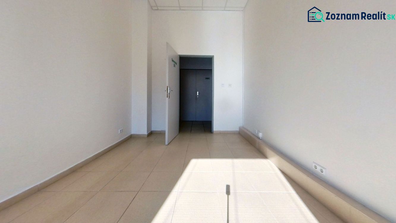 Interiér kanceláře s bílými stěnami a světlým keramickým obkladem podlahy.