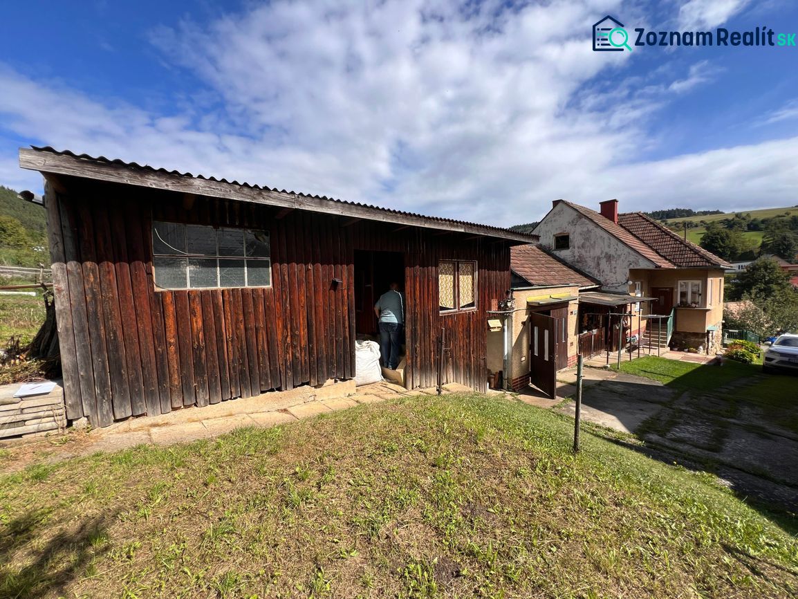 Dvůr rodinného domu v Kalamenoch se zahradním stavem a oblohou s mraky.