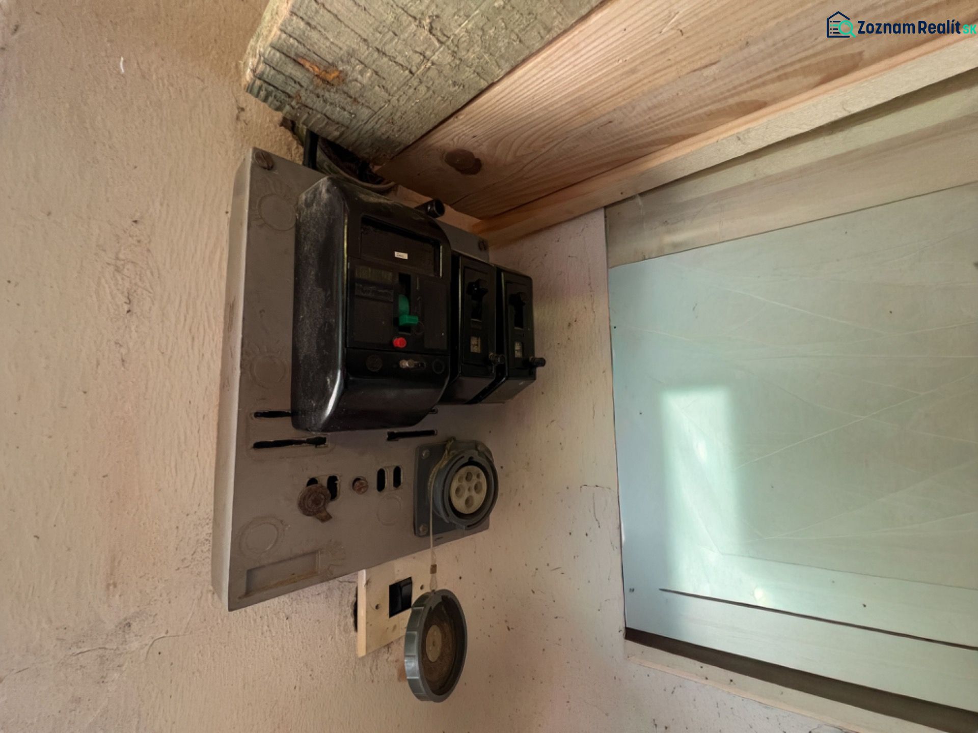 Stará elektrická rozvodná skříň v garáži, se starými jističemi a zásuvkami.