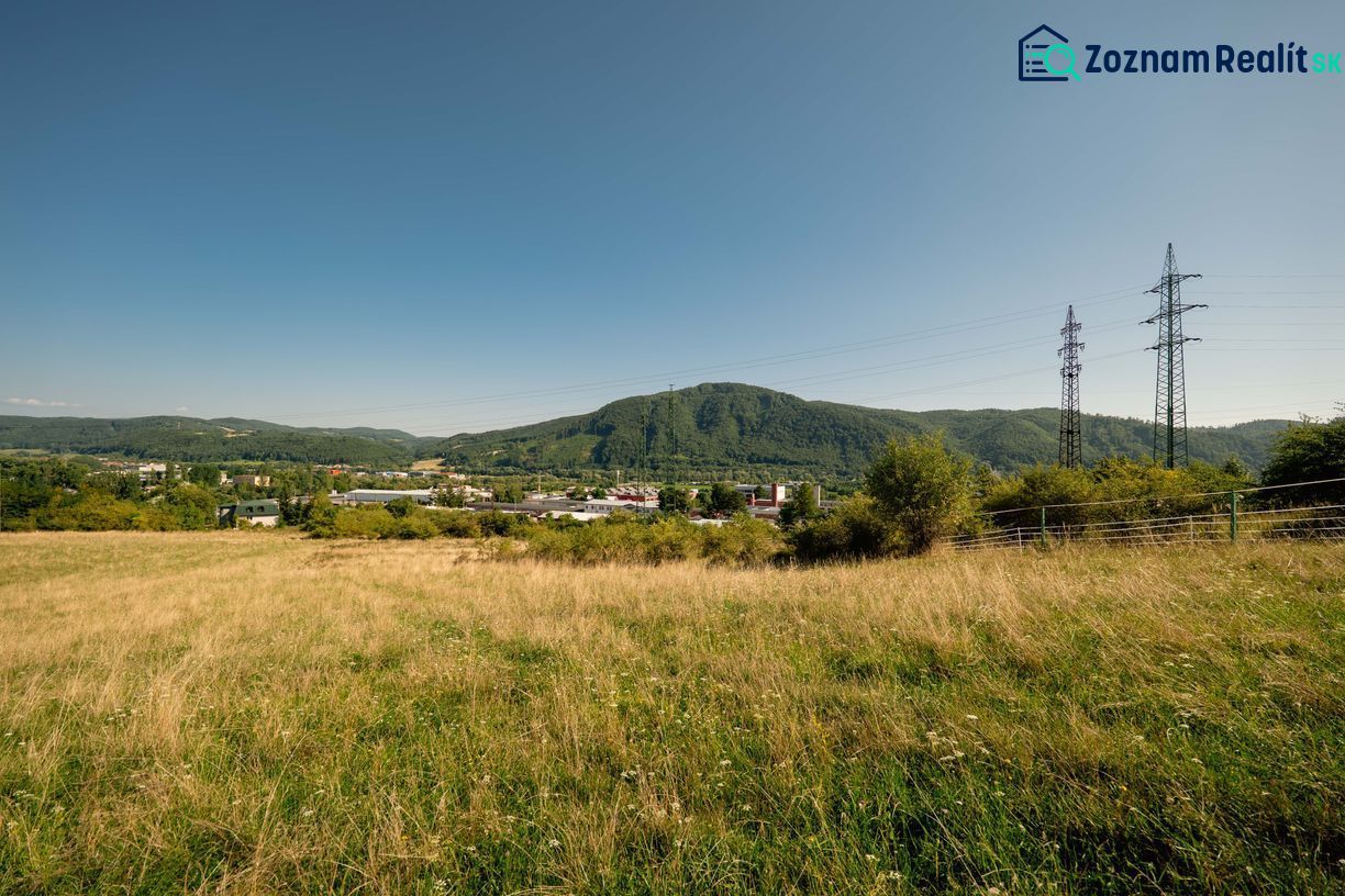 Krajina s travnatým pozemkem a elektrickými sloupy na Partizánské cestě, Banská Bystrica. Pozemky - bydlení.
