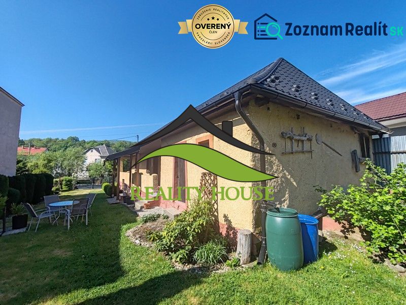 Rodinný dům na Hlavní ulici v Banském s pěkným dvorem, zahradním nábytkem a vegetací.
