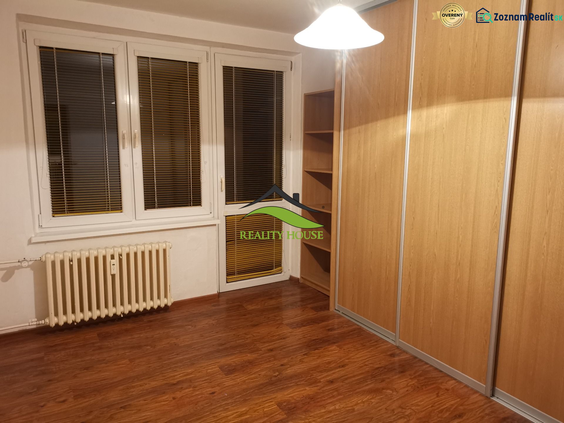 Pokoj s podlahou s dřevěným dekorem a velkou vestavěnou skříní v 3-pokojovém bytě.