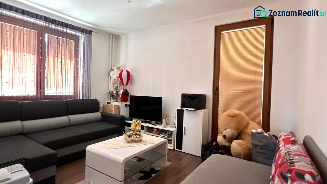 Obývací pokoj v rodinném domě s pohovkou, televizí a dekoracemi.