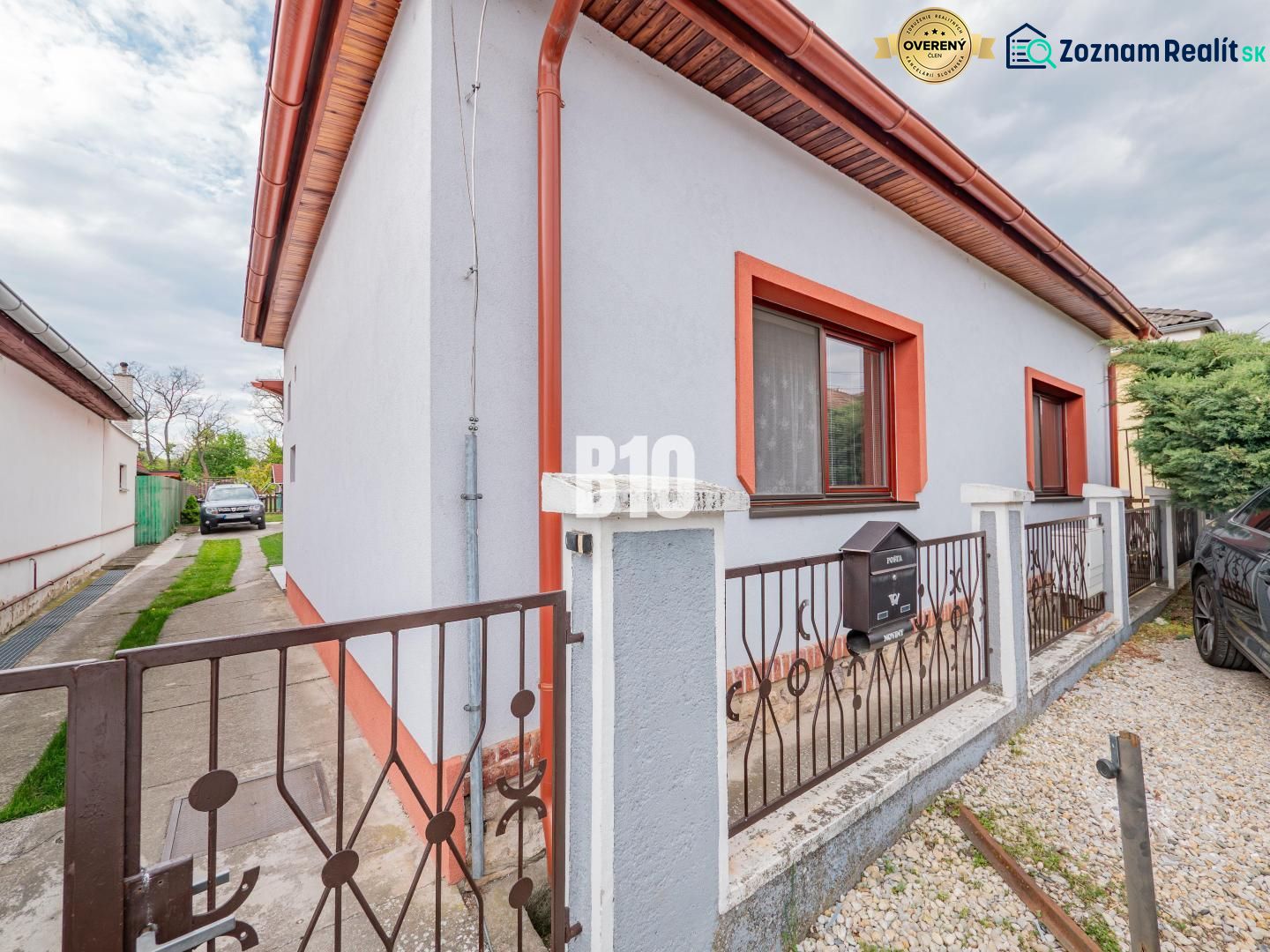Rodinný dům v Nitře s bílou fasádou, červeným lemováním a zahrádkou.