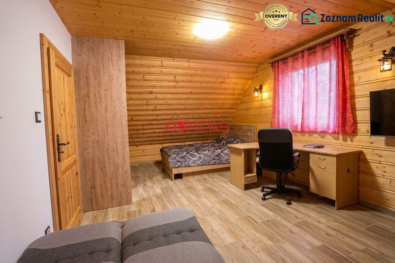 Pokoj v rodinném domě s dřevěnými stěnami, podlahou s dřevěným dekorem a pracovním stolem.
