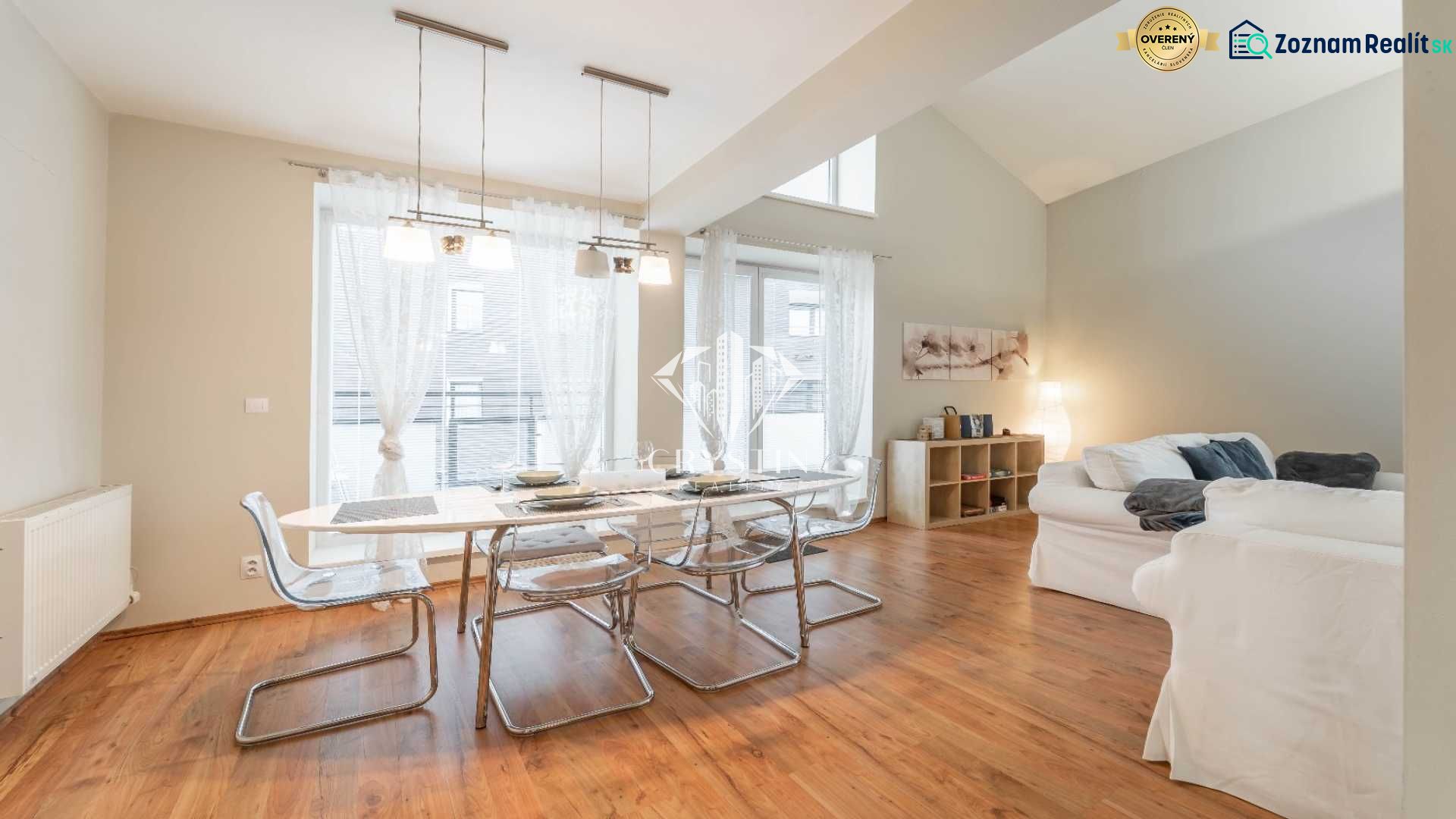 Rekreační apartmán s jídelním stolem, pohodlnými sedačkami a podlahou s dřevěným dekorem.
