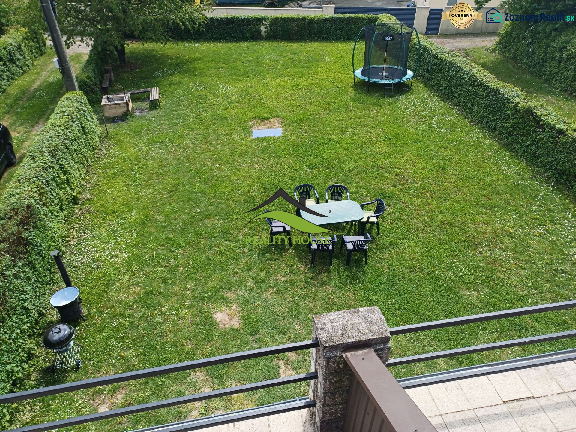 Zahrada u chaty v Kaluži s trampolínou a posezením na trávě.