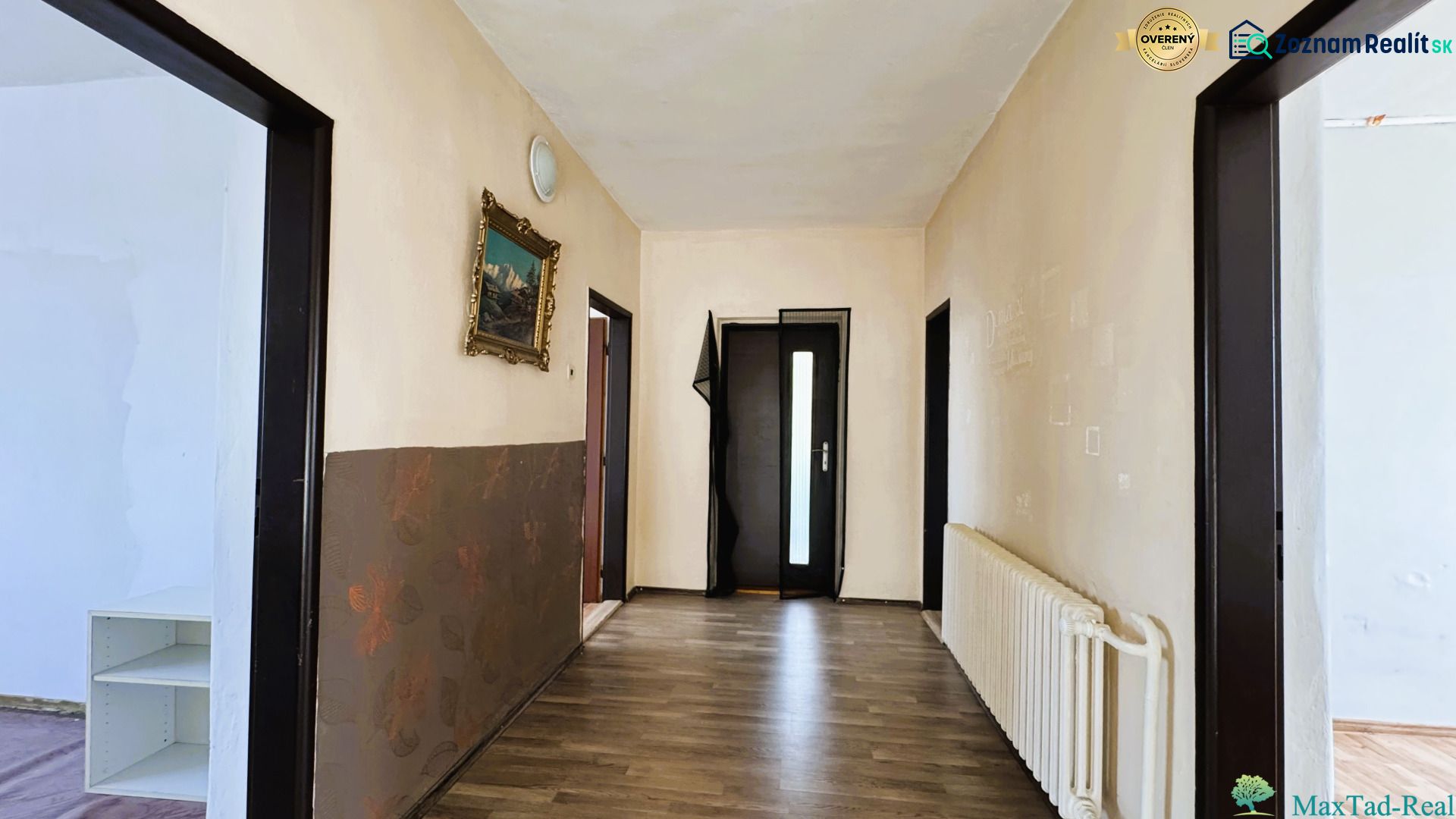 Chodba v rodinném domě s podlahou s dřevěným dekorem a obrazem na stěně.