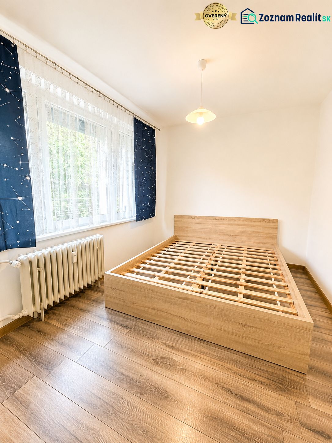 Ložnice s podlahou s dřevěným dekorem a postelí ve 3-pokojovém bytě.