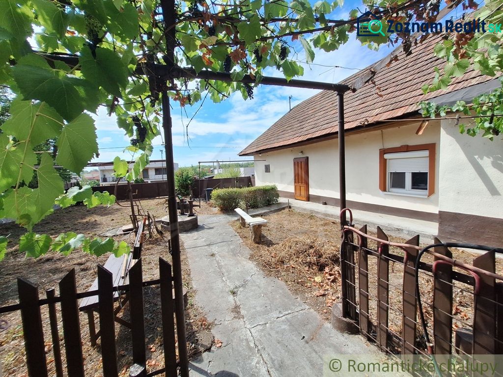 Dvůr u rodinného domu v Kamenici nad Hronom s pergolou a lavičkou.