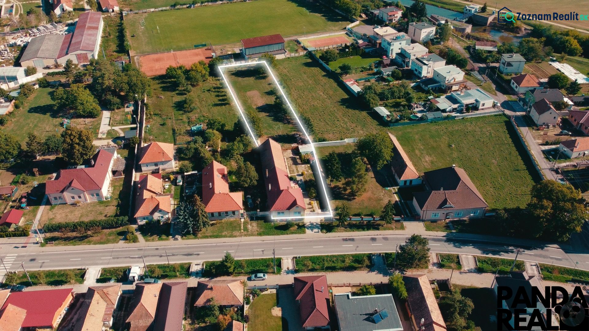 Letecký pohled na rodinné domy a zahrady v Nadlicích, obklopené zelení a cestami.