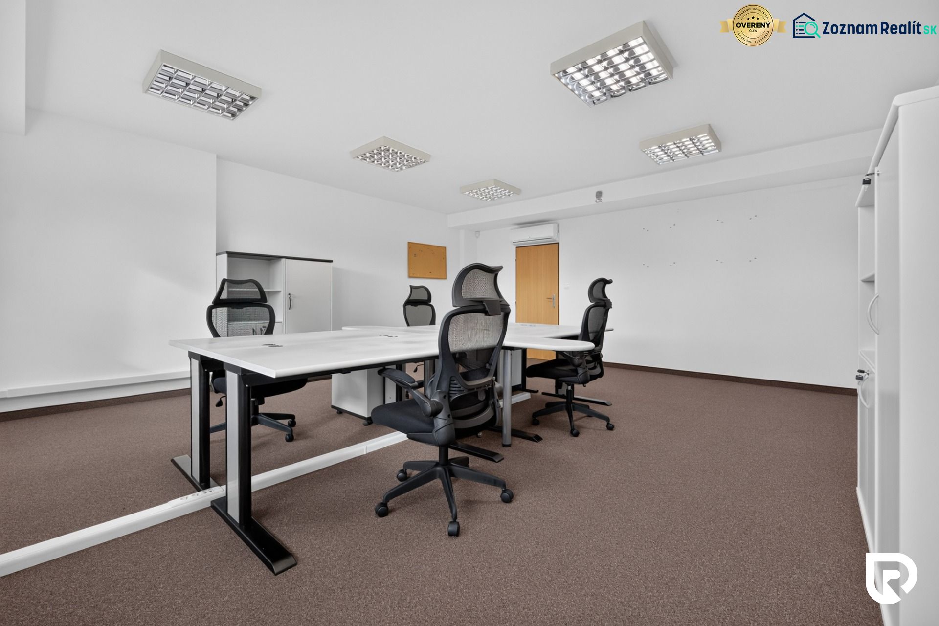 Kanceláře s konferenčním stolem, ergonomickými židlemi a úložnými skříněmi.