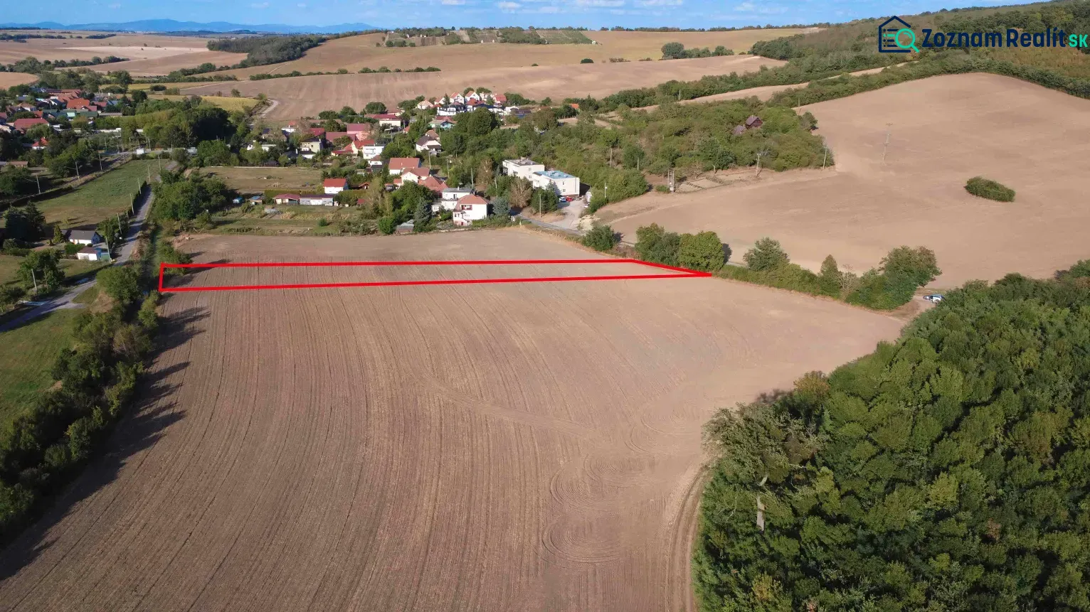 Zemědělské a lesní pozemky v Podhájské, s výhledem na okolní pole a zeleň.