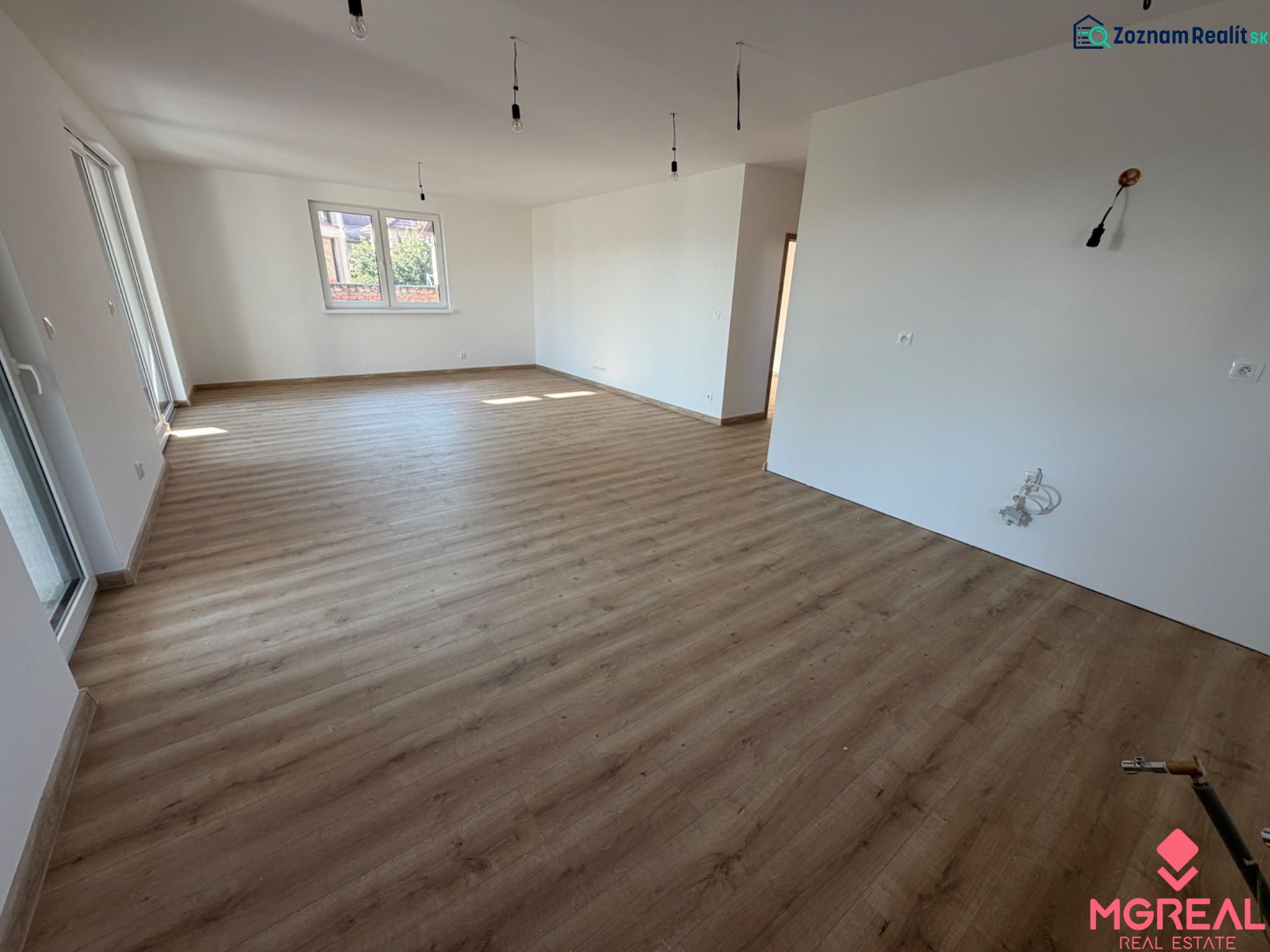 Interiér rodinného domu s podlahou s dřevěným dekorem a bílými stěnami.