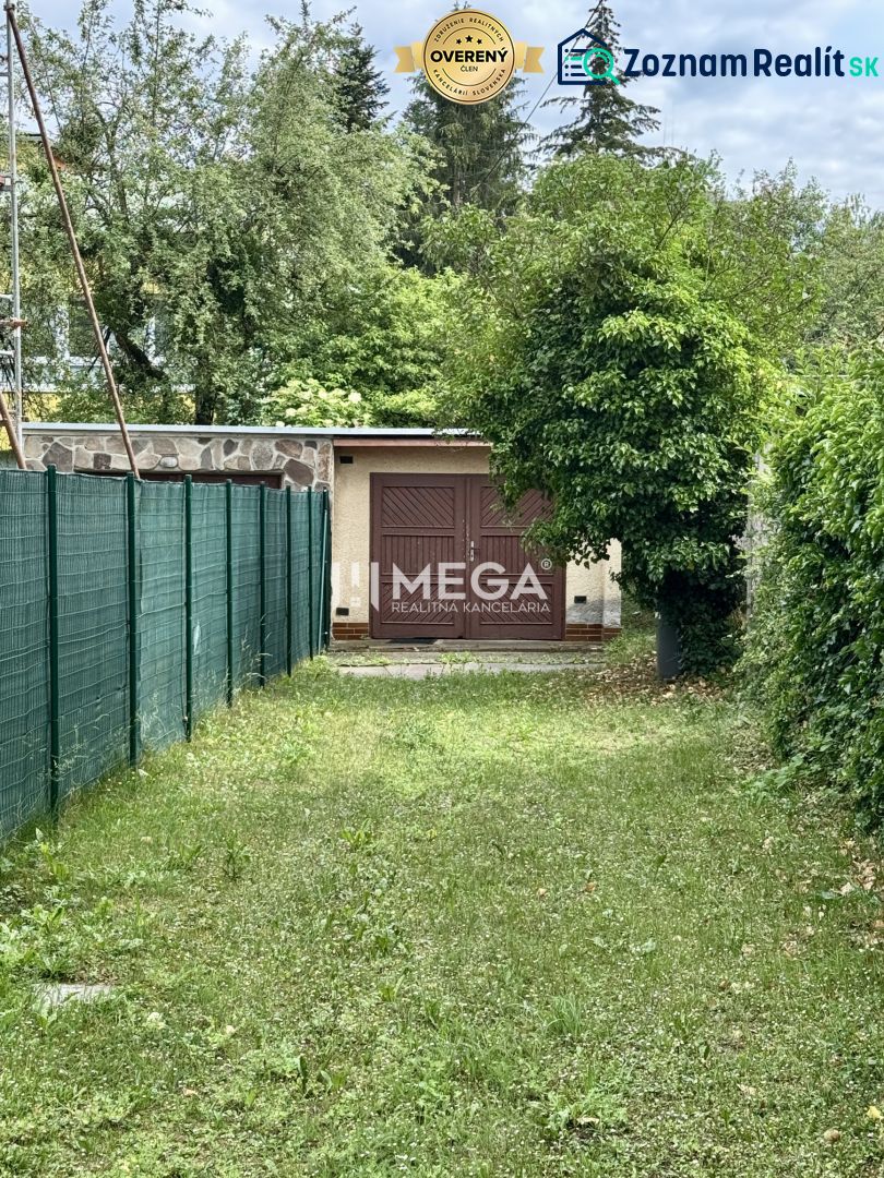 Garáž na ulici Osvoboditelů v Humenném, obklopená zelení a plotem.