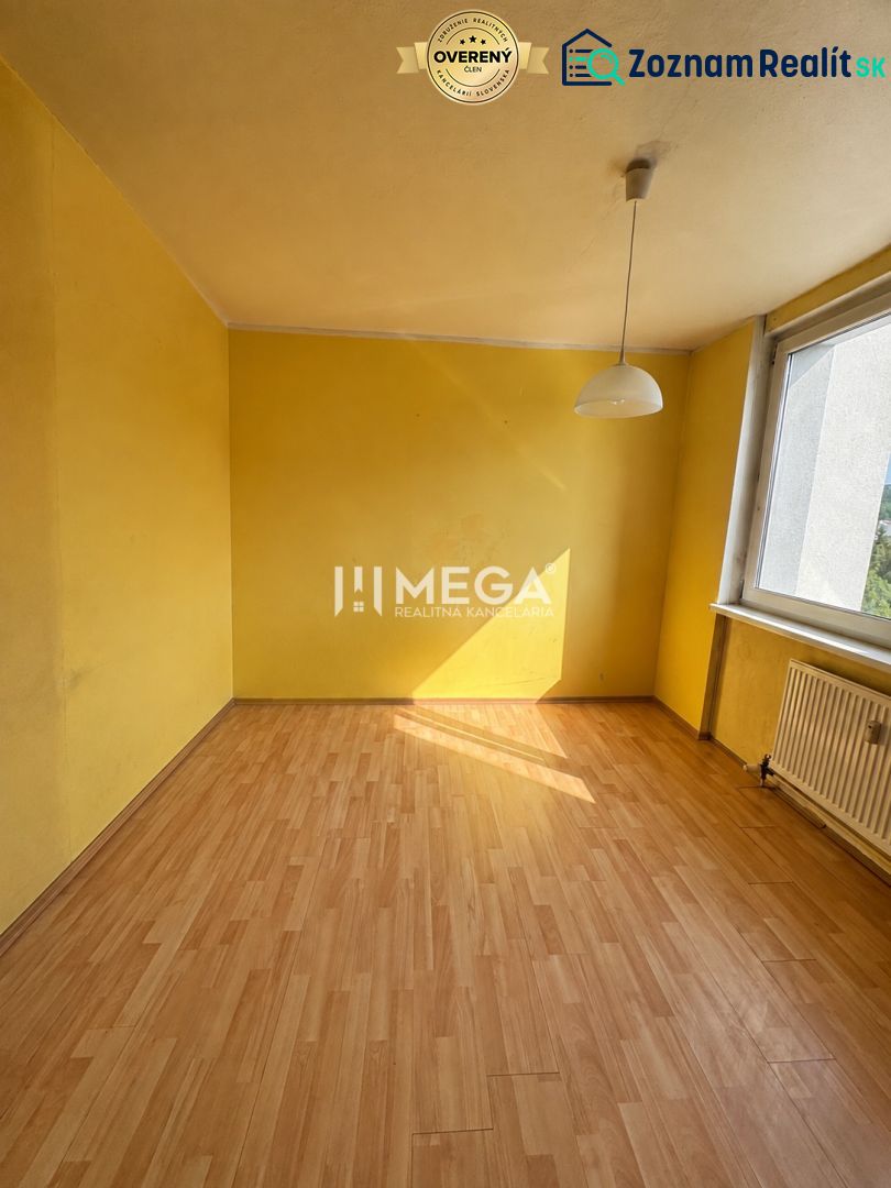 Žlutá místnost s velkým oknem a podlahou s dřevěným dekorem v 3-pokojovém bytě.