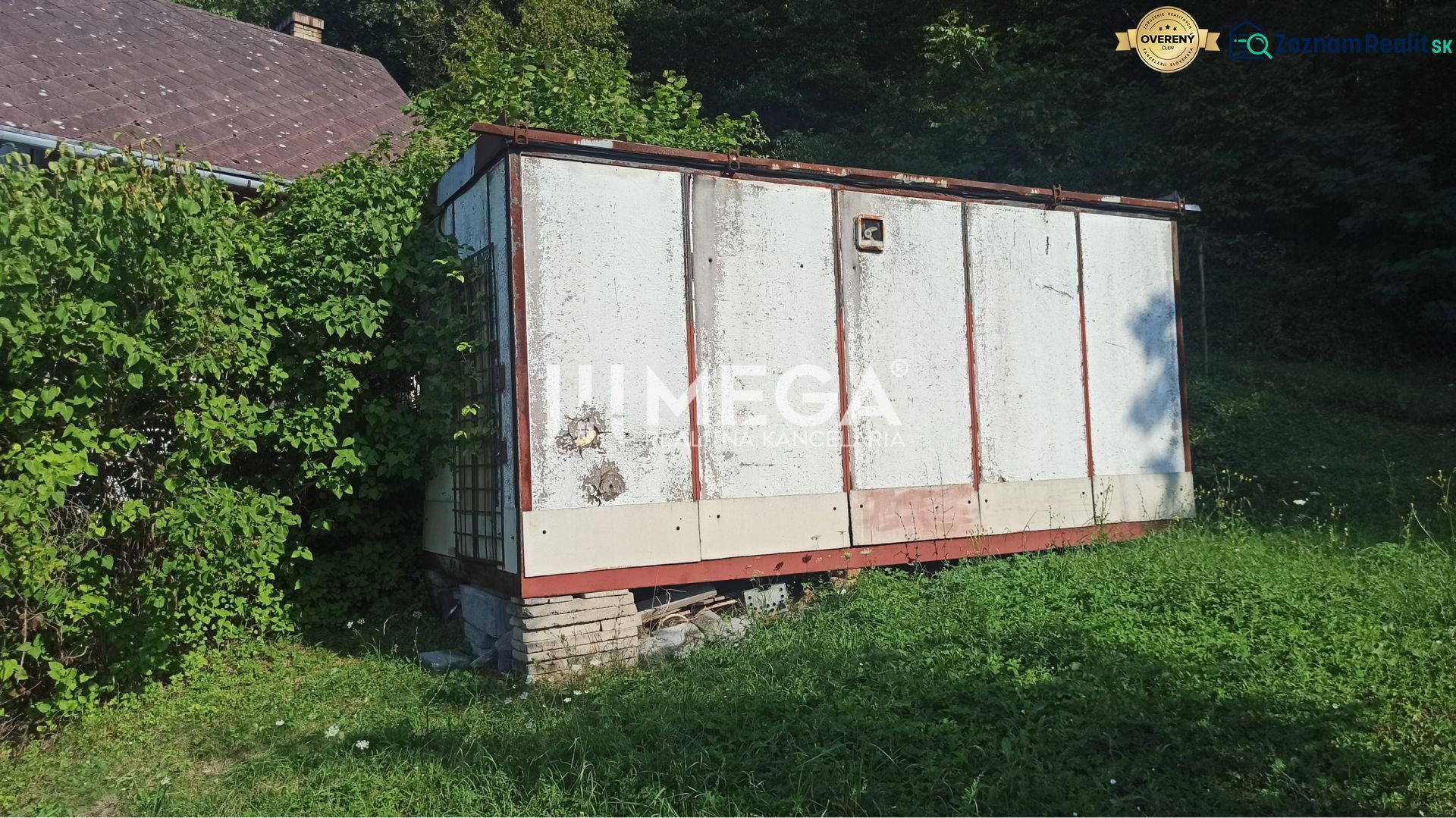 Starší sklad na zahradě ulice v Humenném, obklopený zelení a rostoucí trávou.