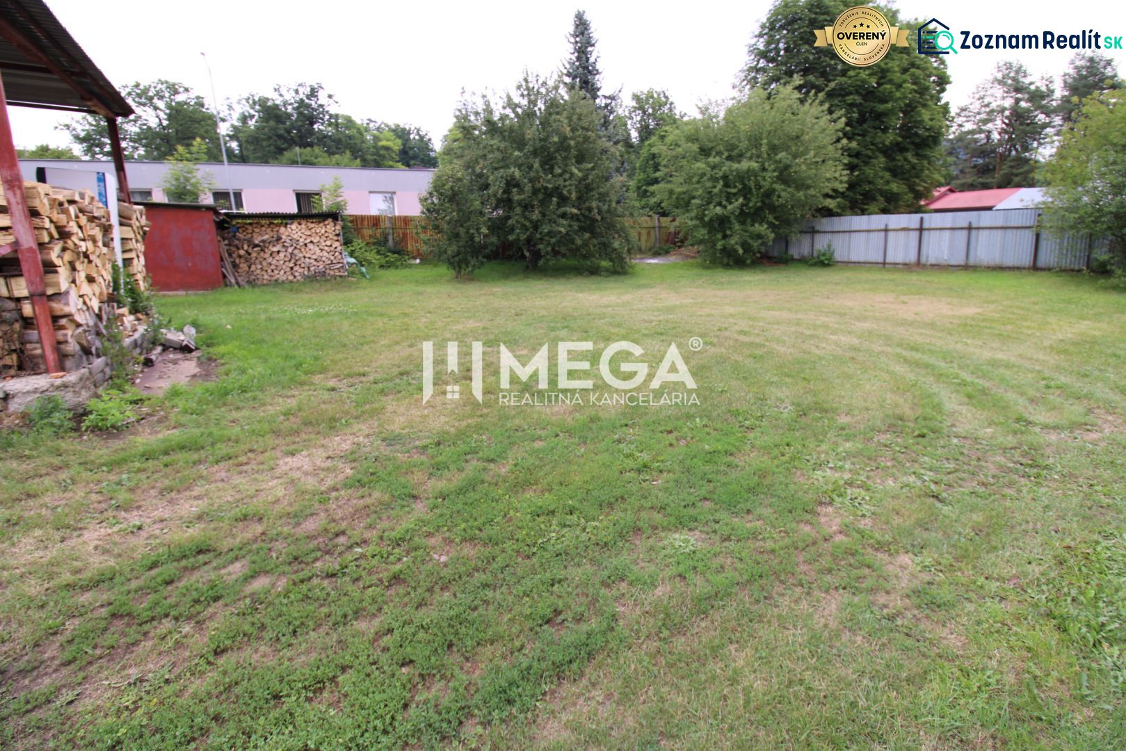 Zahrada u rodinného domu v Uliči na Ulič 131 s dřevěným přístřeškem a stromy.
