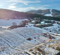 Zimní krajina v Rekreačních pozemcích ve Valči, na ulici Snowland, s horským pozadím.