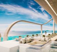 Luxusní bazénová terasa s lehátky a výhledem na oceán v rámci výstavby bytů.