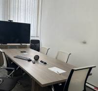 Kanceláře se zasedací místností, stolem, židlemi, televizorem a projektorem na prezentace.