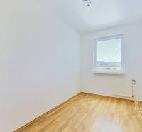 Světlá místnost s laminátovou podlahou a oknem, ideální pro 4pokojový byt.
