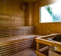 Dřevěná sauna s proskleným oknem a logem realitní kanceláře.