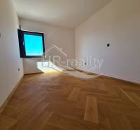 Prostor s dřevěnou podlahou a velkým oknem v rekreačním apartmánu.