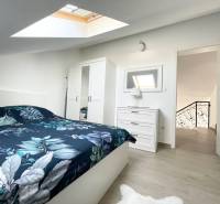 Ložnice v rekreačním apartmánu s postelí, skříní a střešním oknem.