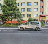 Ulice Landauova v Bratislavě-Dúbravce s obytnou budovou a zaparkovaným autem před ní.