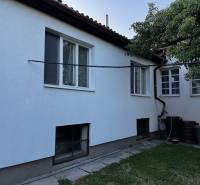 Rodinný dům v Lučenci s bílou fasádou, zahradou a velkými okny.