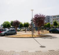 Parkoviště a moderní bytovky v Trenčíně s dětským hřištěm.