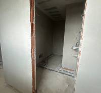 Nedokončená místnost se sítěmi a neomítnutými cihlami v rodinném domě.