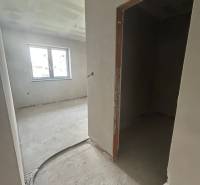 Interiér rodinného domu s nedokončenými stěnami a otevřeným oknem.