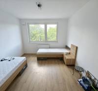 Pokoj s dvěma postelemi a oknem, dřevěná podlaha ve 3-pokojovém bytě.