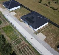 Rodinný dům v Podlužanech s fotovoltaickými panely, zahradou a okolními poli.