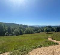 Travnaté pozemky na bydlení v Olešné obklopené lesy s panoramatickým výhledem na kopce.