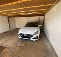 Interiér garáže s bílým autem značky Hyundai zaparkovaným uvnitř.