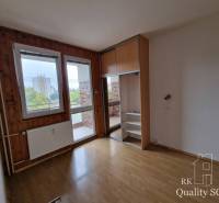 Prázdný pokoj ve čtyřpokojovém bytě s dřevěnými panely a výhledem na balkon.