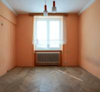 Prázdný pokoj v 2-pokojovém bytě s oranžovými stěnami a dřevěnou podlahou.