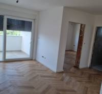 Interiér 4-pokojového bytu s dřevěnou podlahou a velkými okny.